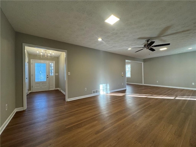 spare room with dark hardwood / wood-style floors, ceiling fan with notable chandelier, and a textured ceiling