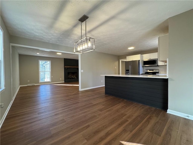 kitchen featuring white cabinetry, hanging light fixtures, a textured ceiling, and appliances with stainless steel finishes