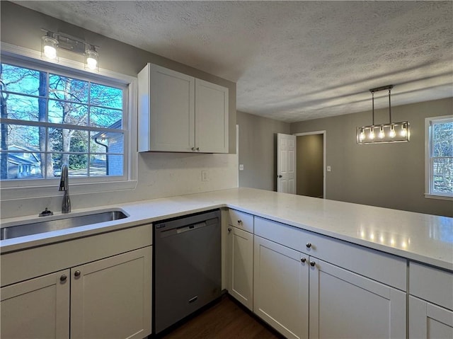 kitchen with decorative light fixtures, dishwasher, sink, white cabinets, and a textured ceiling