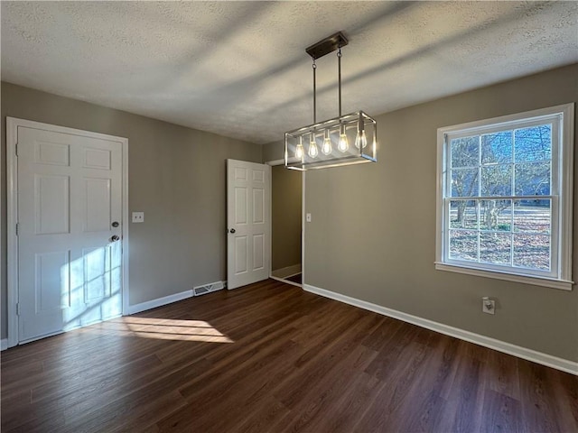 unfurnished dining area featuring dark hardwood / wood-style floors and a textured ceiling