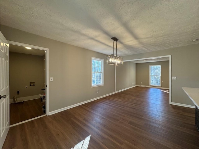 unfurnished dining area with an inviting chandelier, dark hardwood / wood-style floors, and a textured ceiling