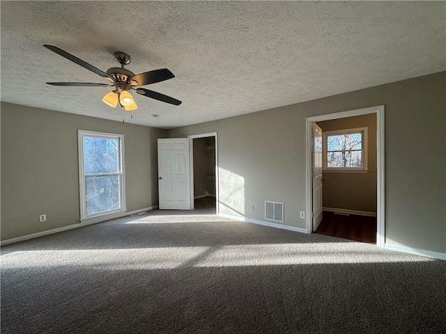 carpeted spare room featuring ceiling fan and a textured ceiling