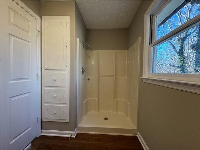 bathroom featuring hardwood / wood-style flooring, a shower, and a textured ceiling