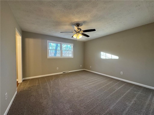 spare room with ceiling fan, dark carpet, and a textured ceiling