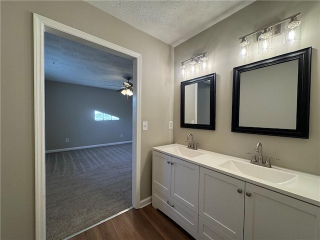 bathroom featuring hardwood / wood-style flooring, ceiling fan, vanity, and a textured ceiling