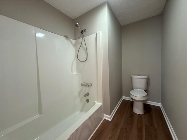 bathroom featuring wood-type flooring, toilet, a textured ceiling, and washtub / shower combination