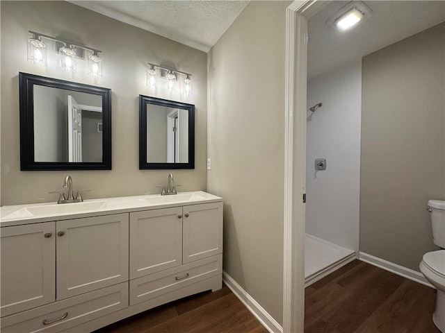 bathroom with hardwood / wood-style flooring, vanity, toilet, and a textured ceiling