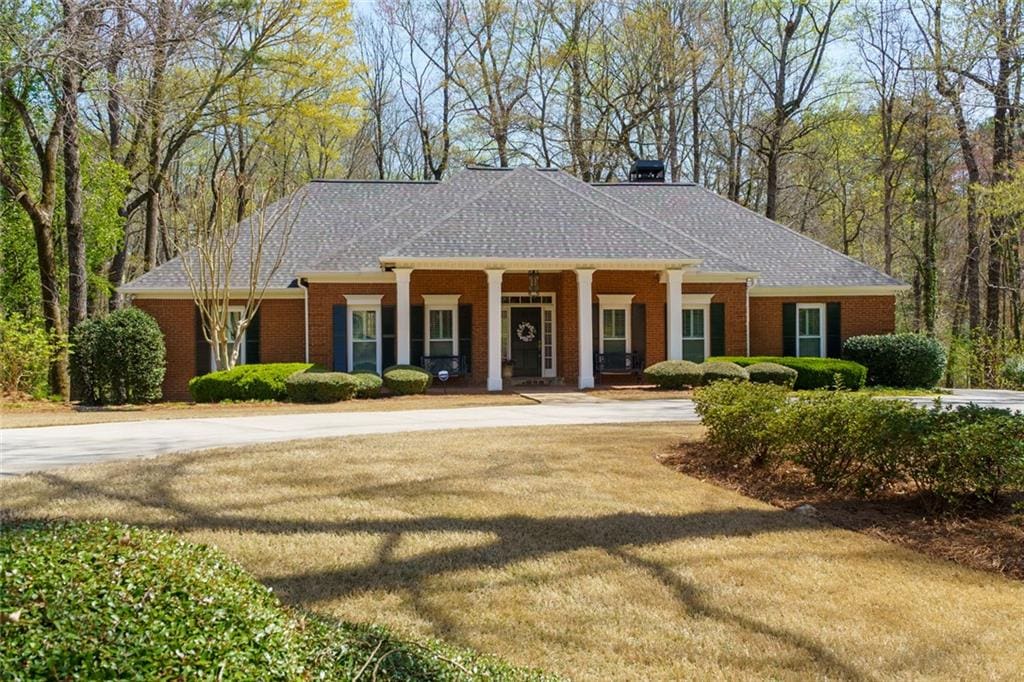 view of front of home with brick siding and roof with shingles