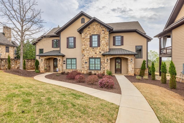 craftsman inspired home featuring a standing seam roof, metal roof, stone siding, a front lawn, and a shingled roof