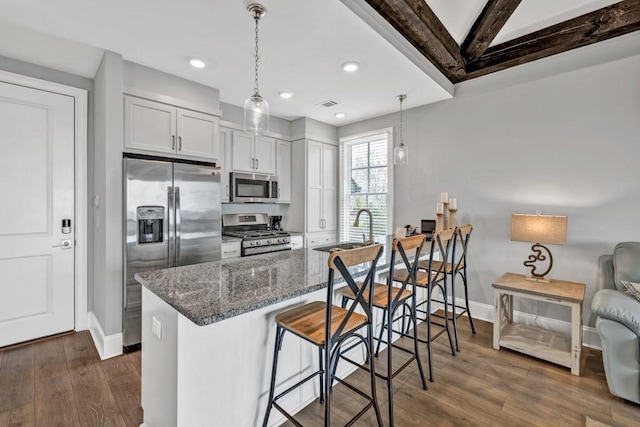 kitchen with dark wood-style floors, dark stone countertops, a sink, and stainless steel appliances