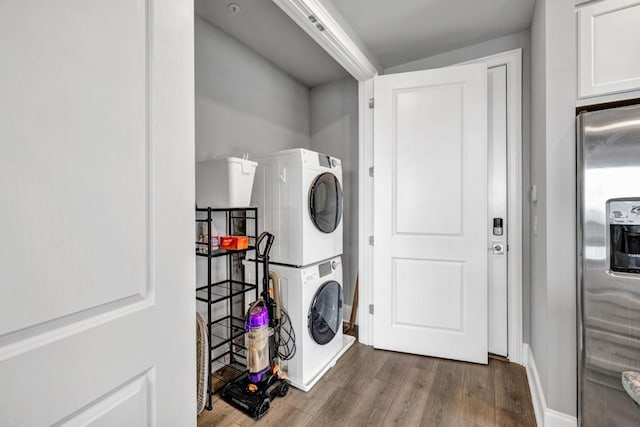 laundry room with stacked washer and dryer, laundry area, and wood finished floors