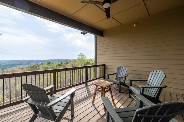 wooden deck with ceiling fan and a forest view