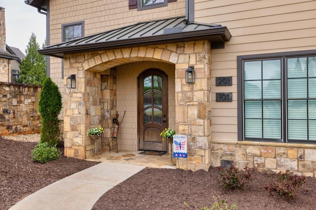 doorway to property featuring stone siding, metal roof, and a standing seam roof