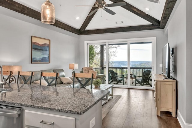 kitchen with lofted ceiling with beams, dark wood finished floors, stainless steel dishwasher, visible vents, and a ceiling fan