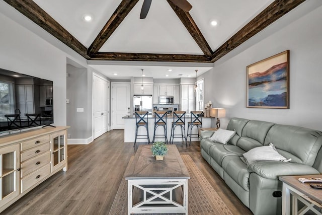 living area featuring a ceiling fan, baseboards, beamed ceiling, and dark wood finished floors