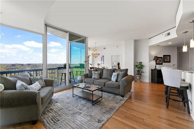 living room featuring a water view, a notable chandelier, light hardwood / wood-style flooring, and a wall of windows