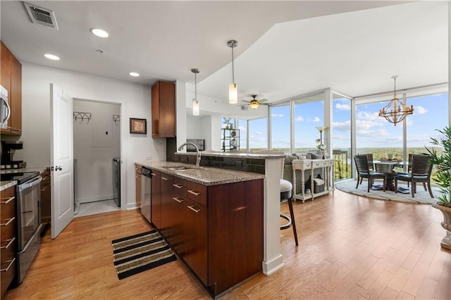 kitchen featuring kitchen peninsula, stainless steel appliances, sink, a breakfast bar, and light wood-type flooring