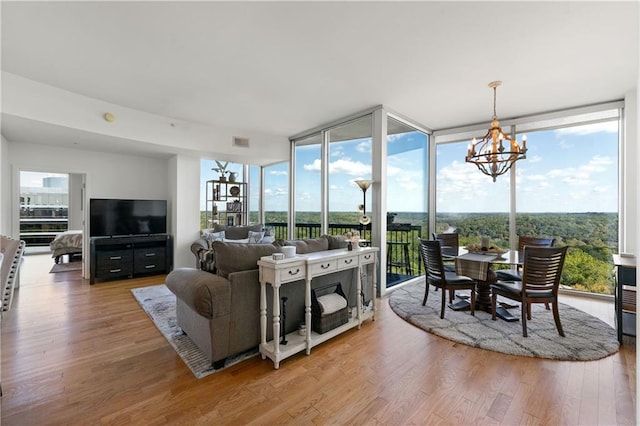 living room featuring a notable chandelier, hardwood / wood-style floors, a wall of windows, and a healthy amount of sunlight