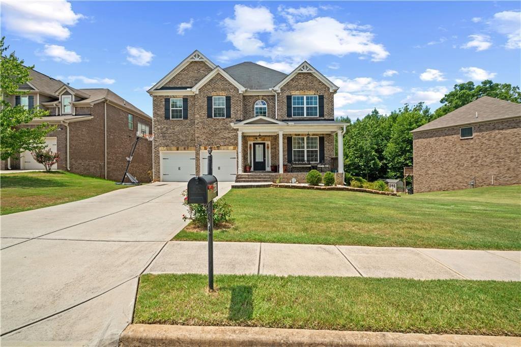 view of front of property featuring a garage, concrete driveway, brick siding, and a front yard