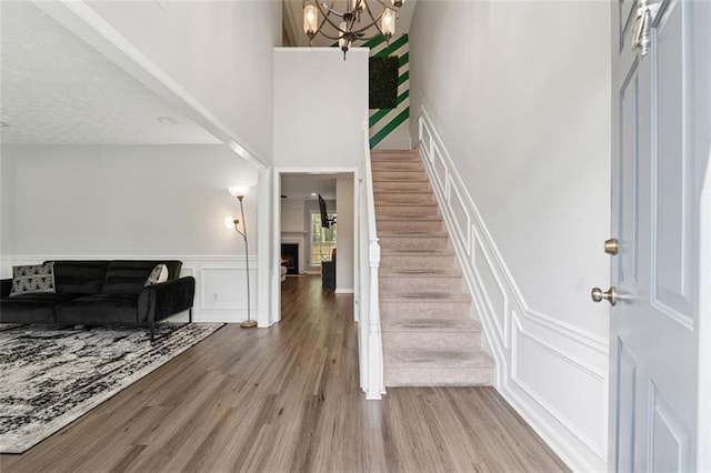 4147 Pinehurst Valley Dr, Decatur, GA 30034 - foyer entrance featuring a decorative wall, stairs, wood finished floors, a chandelier, and a warm lit fireplace