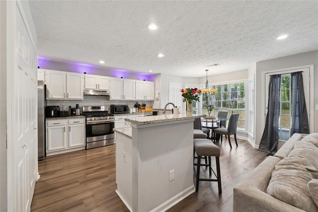 4147 Pinehurst Valley Dr, Decatur, GA 30034 - kitchen with appliances with stainless steel finishes, under cabinet range hood, open floor plan, white cabinets, and a breakfast bar