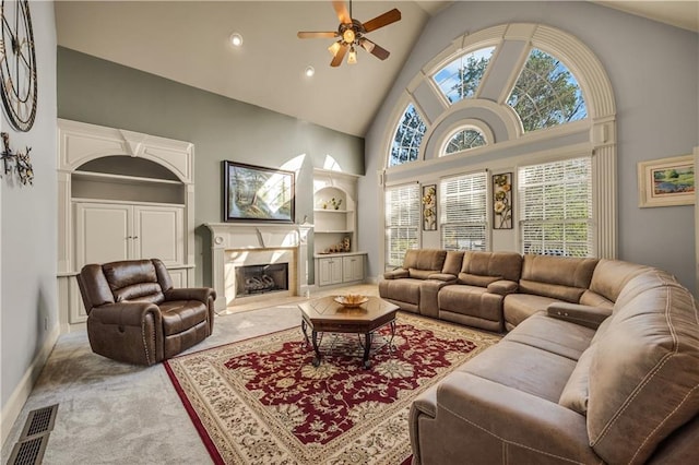 3855 Greenside Ct, Dacula, GA 30019 - carpeted living room with visible vents, built in features, ceiling fan, high vaulted ceiling, and a premium fireplace