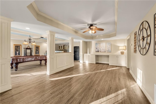 3855 Greenside Ct, Dacula, GA 30019 - unfurnished living room with crown molding, ceiling fan, light wood-style floors, ornate columns, and a tray ceiling