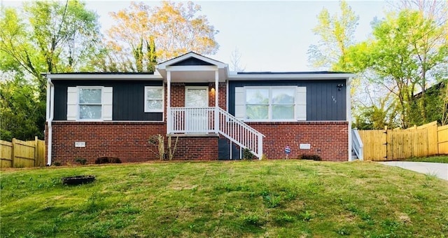 view of front of property with fence, a front lawn, brick siding, and board and batten siding