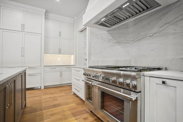 kitchen with light hardwood / wood-style flooring, backsplash, double oven range, white cabinets, and custom range hood