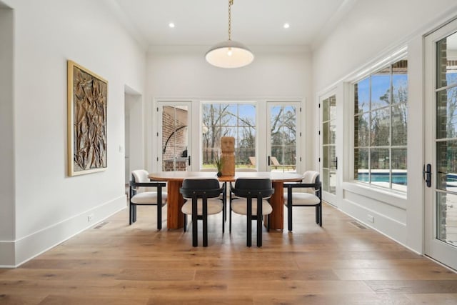 dining space with light hardwood / wood-style floors and ornamental molding