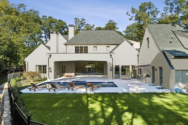 back of house with an outdoor kitchen, outdoor lounge area, a patio area, a yard, and a fenced in pool