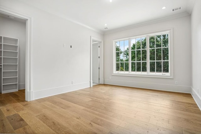 spare room with light hardwood / wood-style floors and crown molding