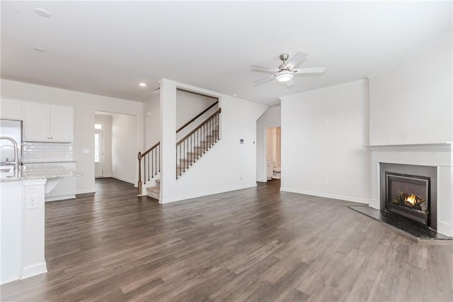 6706 Moondancer Ct, Flowery Branch, GA 30542 - unfurnished living room with dark wood finished floors, stairway, a warm lit fireplace, ceiling fan, and recessed lighting