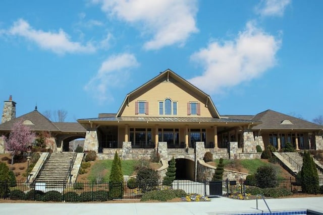 6706 Moondancer Ct, Flowery Branch, GA 30542 - dutch colonial featuring a gambrel roof, a fenced front yard, stone siding, stairs, and a porch
