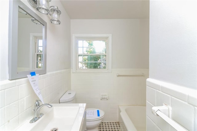 full bath with a sink, a wainscoted wall, toilet, and a washtub