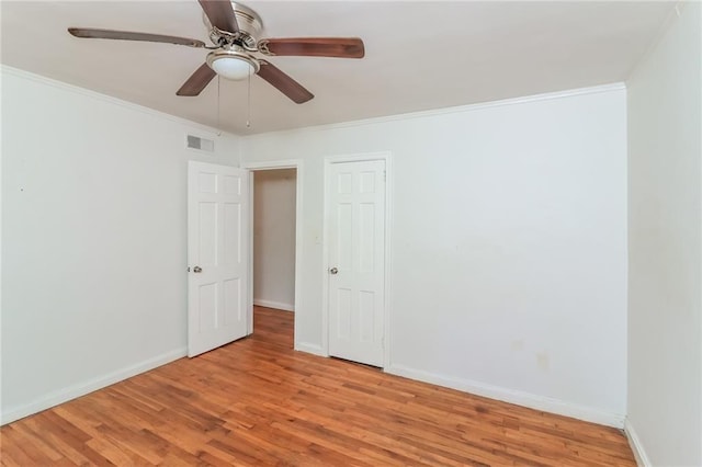 unfurnished room with visible vents, light wood-style flooring, baseboards, and ornamental molding