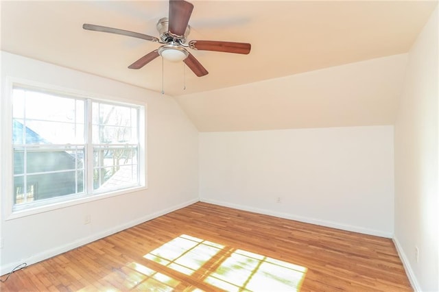 additional living space with light wood-style flooring, a ceiling fan, baseboards, and vaulted ceiling