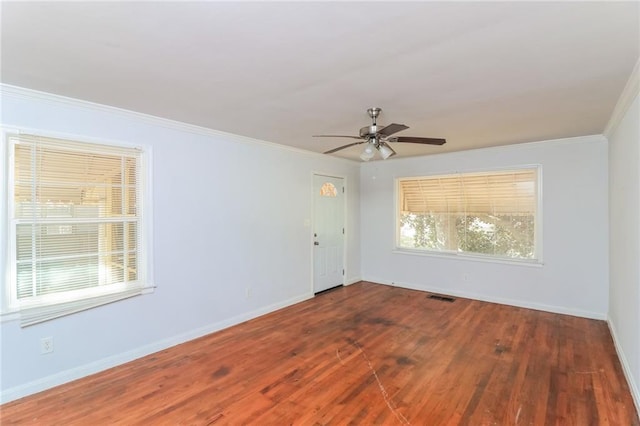 spare room with visible vents, baseboards, ornamental molding, wood finished floors, and a ceiling fan