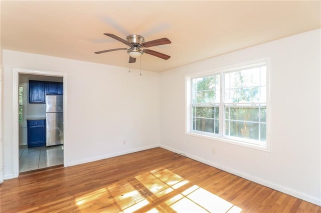 empty room featuring baseboards, light wood-style floors, and ceiling fan