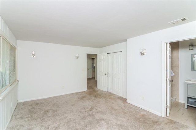 spare room featuring light colored carpet, visible vents, and baseboards