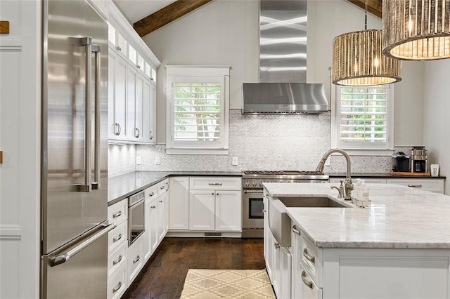 kitchen featuring lofted ceiling with beams, wall chimney exhaust hood, premium appliances, and tasteful backsplash