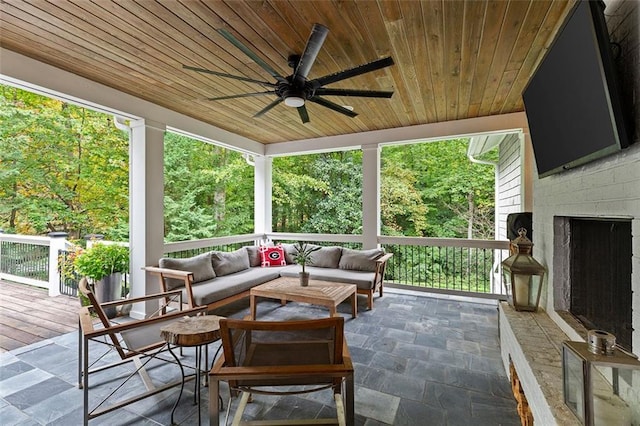 sunroom with wooden ceiling, ceiling fan, and an outdoor brick fireplace