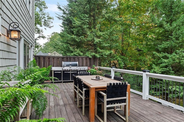 wooden terrace featuring outdoor dining space, grilling area, and fence