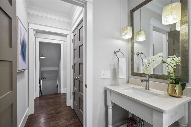 bathroom with ornamental molding, a sink, and wood finished floors