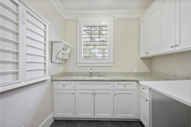 washroom with baseboards, dark tile patterned floors, ornamental molding, and a sink