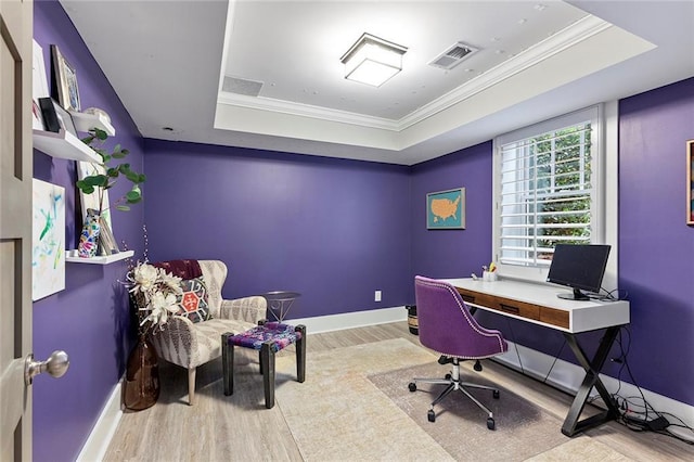 office area with visible vents, a tray ceiling, wood finished floors, and ornamental molding