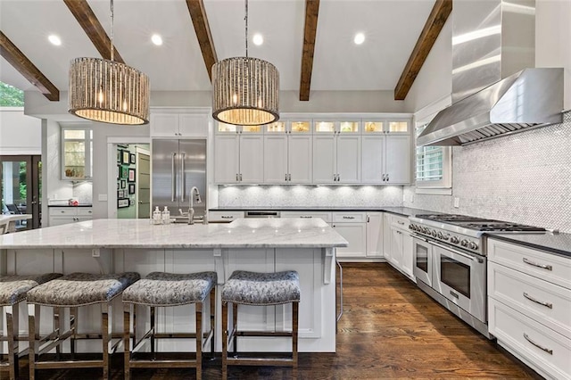 kitchen featuring white cabinets, high end appliances, wall chimney exhaust hood, light stone countertops, and a sink