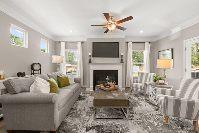 living room featuring ornamental molding, a glass covered fireplace, a ceiling fan, and recessed lighting