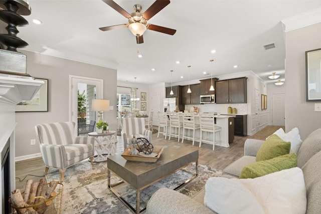 living room with visible vents, light wood-style flooring, ceiling fan, ornamental molding, and recessed lighting