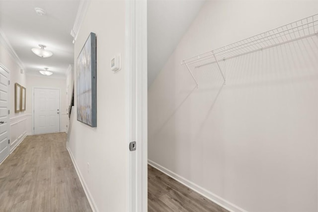 hallway with baseboards, ornamental molding, and wood finished floors